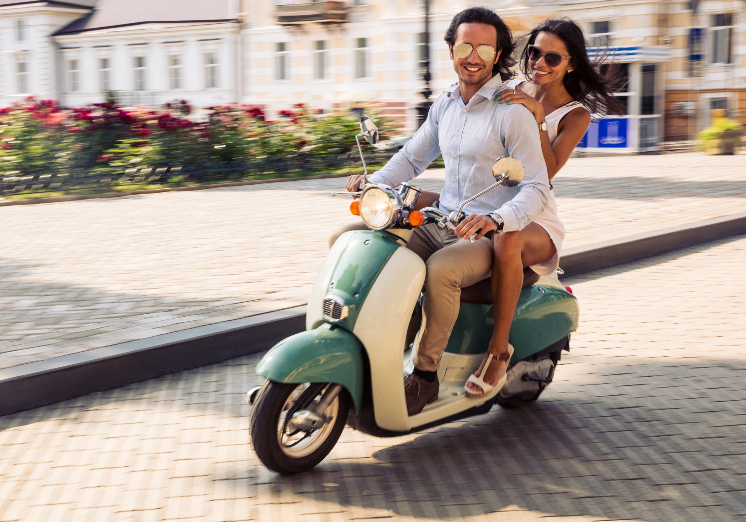 Pareja feliz montando en una scooter en la vieja ciudad europea